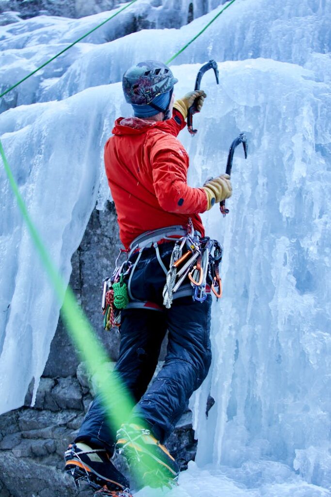 pexels photo 11212984 Ice climber in red jacket ascends frozen waterfall in Alberta, Canada. Vertical shot captures thrilling adventure.