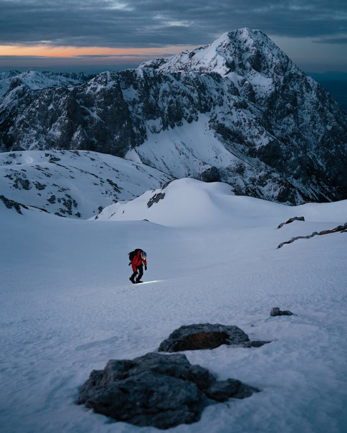 pexels photo 3848197 Lone mountaineer trekking up a snow-covered peak at sunrise in Slovenia.